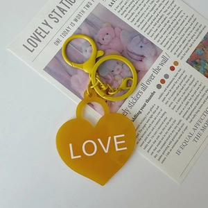 Détail d'un porte-clés jaune en forme de cœur avec texte LOVE et fermoir mousqueton assorti