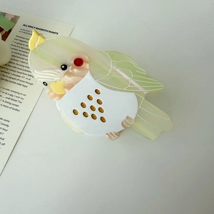 Detail of a handmade parrot claw clip with pearlescent texture and bird-shaped design