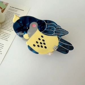 Detail view of a large parrot-shaped hair claw clip made of blue marble acetate material