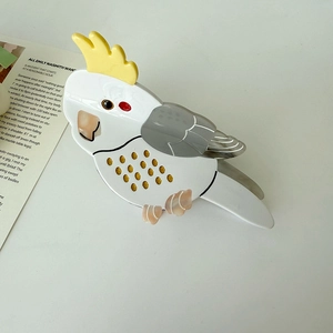 Detail of creative parrot hair claw clip made of acetate with yellow crest and gold dots