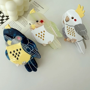 Three colorful parrot-shaped acetate hair claws in blue, green, and grey patterns