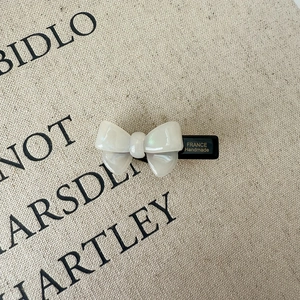 Detailed macro view of cream acetate bow hair clip with golden France Handmade logo