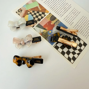 Elegant acetate bow hair clip with France Handmade lettering on an aesthetic background