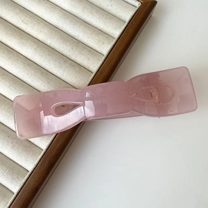 Dettaglio macro di una grande pinza per capelli rosa opaco con finitura liscia e molla