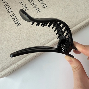 Détail montrant les dents internes et la forme banane de la pince à cheveux noire