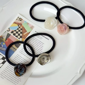 Set of four elegant resin rose hair ties in various colors on a white display tray