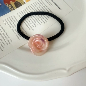 Detail of pink resin rose hair tie with texture on a decorative white ceramic plate