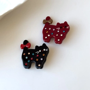 Detail of acetate cat hair clips with colorful rhinestones and ribbon bow accents