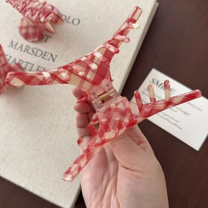 Dettaglio molletta per capelli in acetato a quadretti rossi e bianchi con molla dorata