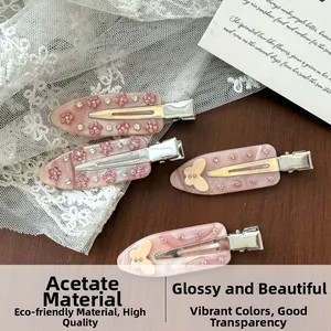 Detailed macro view of pink acetate hair clips with floral and butterfly rhinestone designs