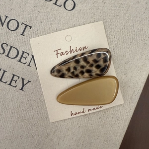 Detail view of acetate tortoise shell and yellow duckbill hair clips on a card