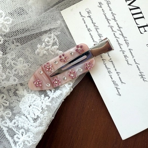 Detail of pink marble acetate hair clip with delicate rhinestone flower and silver metal clip