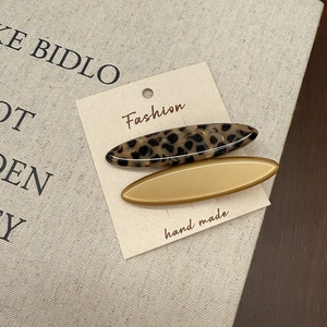 Detailed macro view of two acetate oval hair clips in tortoiseshell and mustard yellow