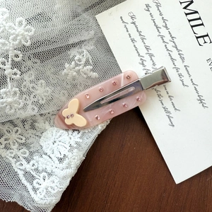 Detail of pink marble acetate hair clip with rhinestones and yellow butterfly on lace