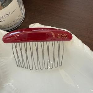 Detailed macro view of wine red acetate hair comb with gold France Handmade logo