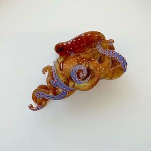 Close-up detail of octopus hair claw clip with amber resin finish and blue suction cups