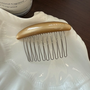 Macro shot of caramel resin hair comb with silver metal teeth in shell tray decor
