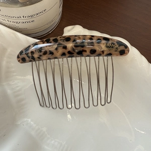 Detailed close-up of a leopard print acetate hair comb with golden France Handmade logo