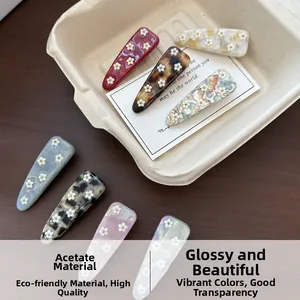 Detail view of colorful acetic acid hair clips with white floral accents on wooden tray