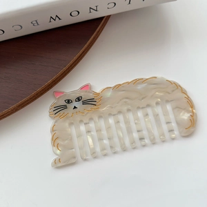 Close-up of the cat-shaped hair comb featuring a pearlescent texture and gold detail