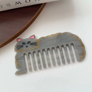 Macro shot of a grey acetate cat-shaped hair comb with marble texture and golden outlines