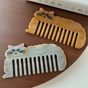 Cute cat-shaped acetate hair combs in amber and marble textures on a wooden surface