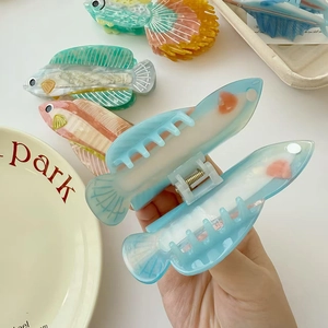 Détail de la pince à cheveux en acétate en forme de poisson avec texture marbrée chic