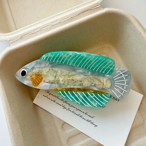 Détail de la pince à cheveux en acétate en forme de poisson, tons vert menthe et blanc