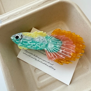 Détail d'une pince à cheveux en forme de poisson tropical en acétate dégradé vert et orange