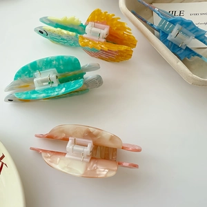 Vue détaillée de pinces à cheveux en acétate en forme de poisson aux tons pastels