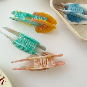 Gros plan de pinces à cheveux en acétate avec textures marbrées et motifs de poissons