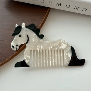 Gros plan d'un peigne à cheveux en acétate en forme de cheval blanc et noir sur bois