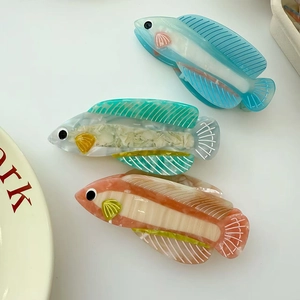 Détail de trois pinces à cheveux en acétate en forme de poisson, finitions marbre coloré