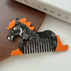 Détail d'un peigne en acétate marbré en forme de cheval avec finitions orange