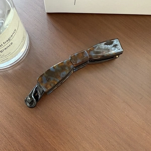 Détail de la pince à cheveux banane avec motif écaille de tortue sur surface en bois
