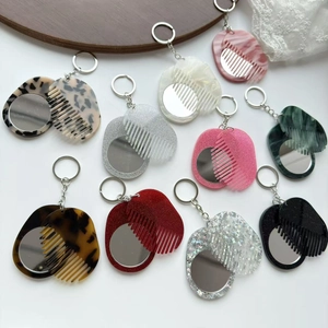 Macro shot of stylish 2-in-1 folding travel hair brush mirror keychains in various patterns