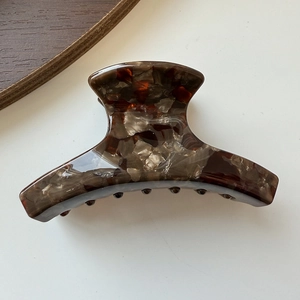 Close-up of small acetate hair claw clip with amber marble texture and glossy resin finish