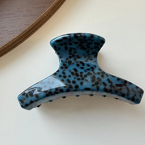 Detail view of small blue leopard print acetate hair claw clip with smooth glossy finish