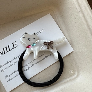 Détail d'un chouchou chat en résine marbrée blanche avec collier strass rose et nœud marron