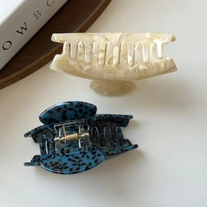 Close-up of small acetate hair claws in marble white and tortoiseshell blue patterns