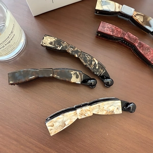 Cinq pinces à cheveux banane en acétate marbré sur une surface en bois sombre