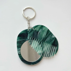 Detail of green marble texture portable mirror and comb set with silver metal keychain