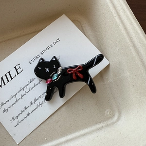 Détail d'une pince à cheveux chat noir avec gemmes colorées et petit nœud rouge