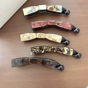 Cinq barrettes bananes aux motifs marbre et écaille de tortue sur fond en bois sombre