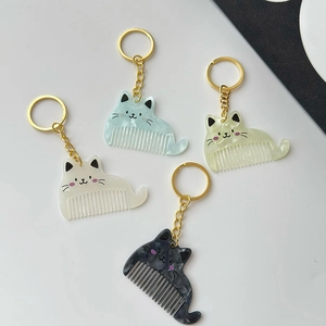 Set of four cute cat-shaped mini combs in marble textured colors with gold keychains