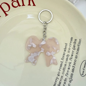 Porte-clés nœud en acide acétique marbré rose et blanc sur une assiette en porcelaine crème