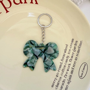 Détail d'un porte-clés nœud en acétate à motif marbre vert sur une assiette en céramique