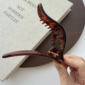 Detail view of tortoiseshell resin hair clip with interior teeth and metal spring mechanism
