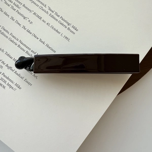 Close-up of minimalist dark brown acetate hair clip on a vintage magazine background