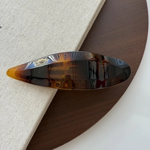Macro shot of polished amber-colored hair clip with tortoise shell pattern on wood texture